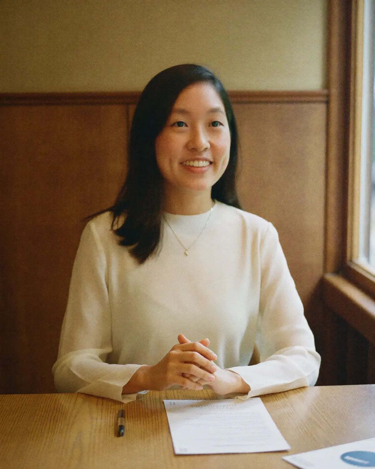 Jessin at a table, the papers in front of her, listening. A representative scene.