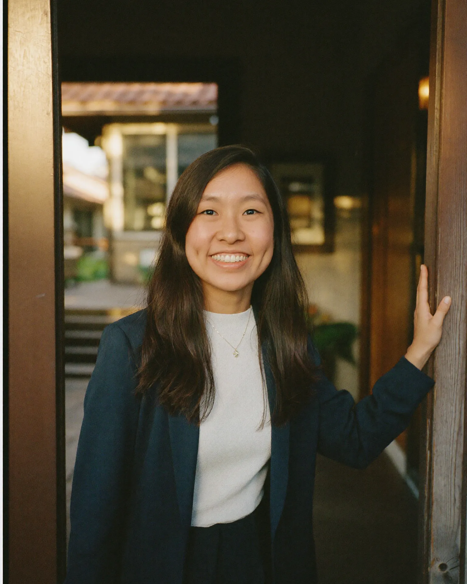 Jessin at the open doorway of a timber house in soft golden light.