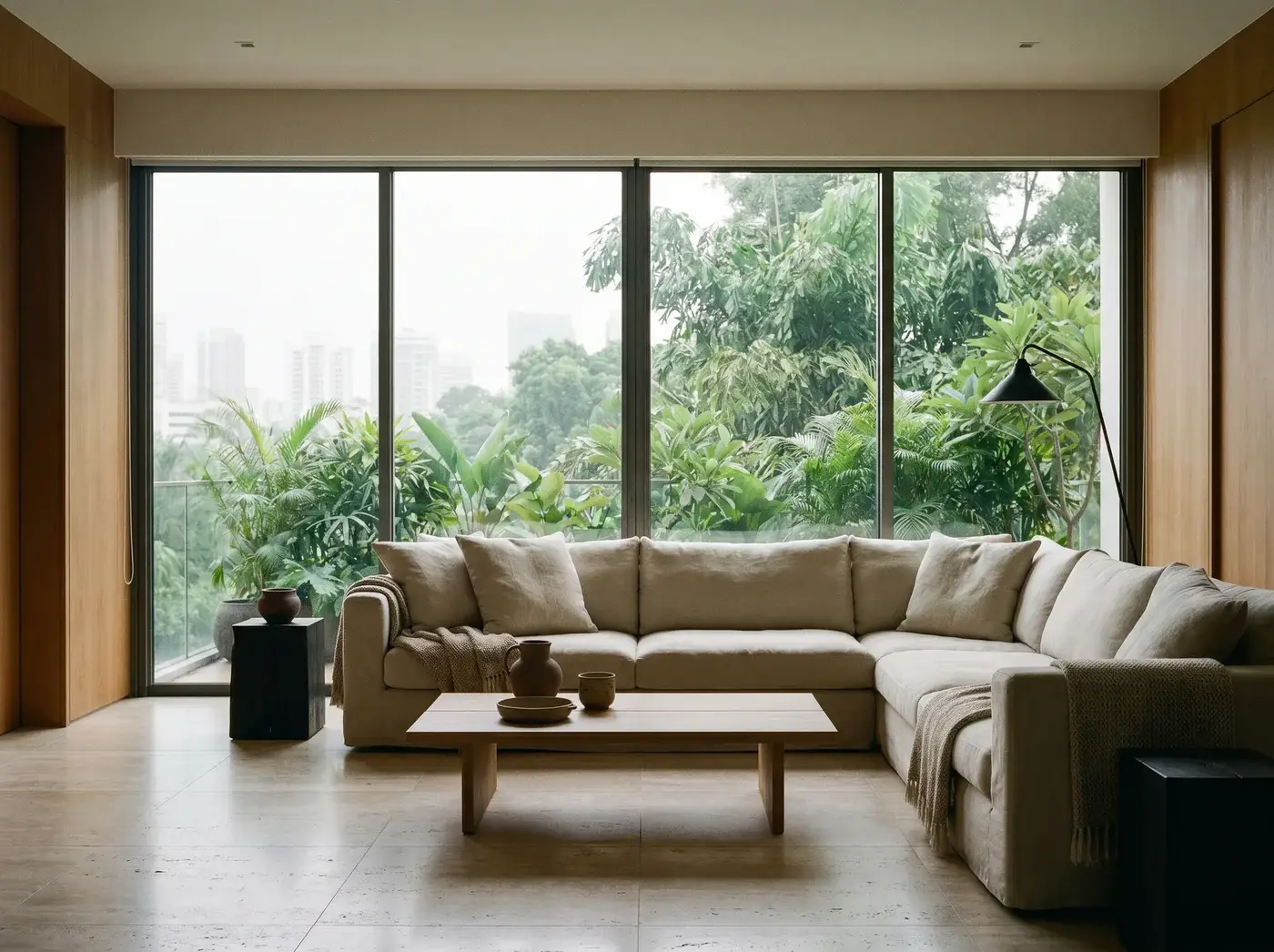 A calm living room in a prime-district home, full-height glass looking over green canopy to the skyline.
