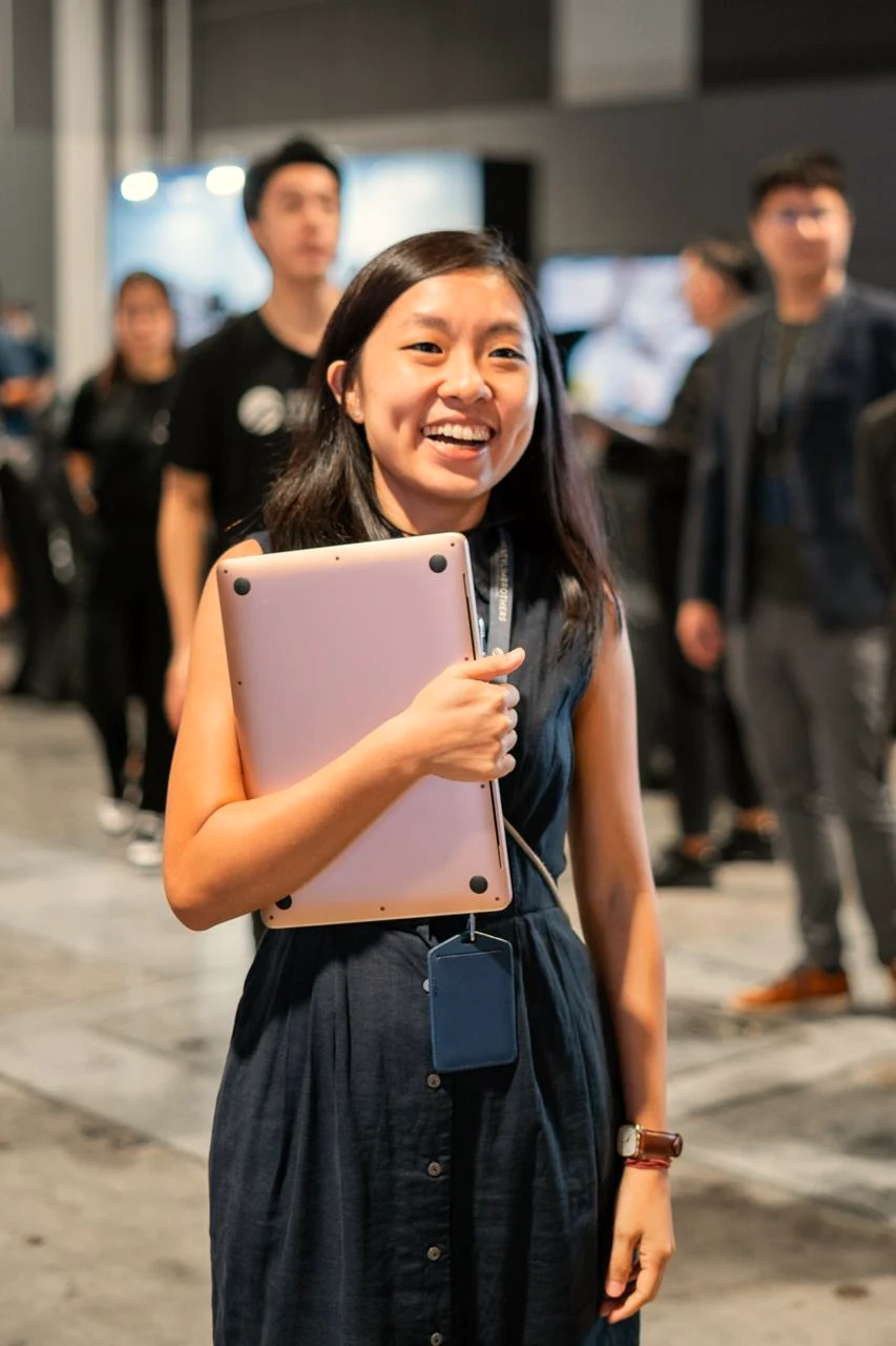 Jessin Chua laughing, laptop under one arm, at an industry gathering.