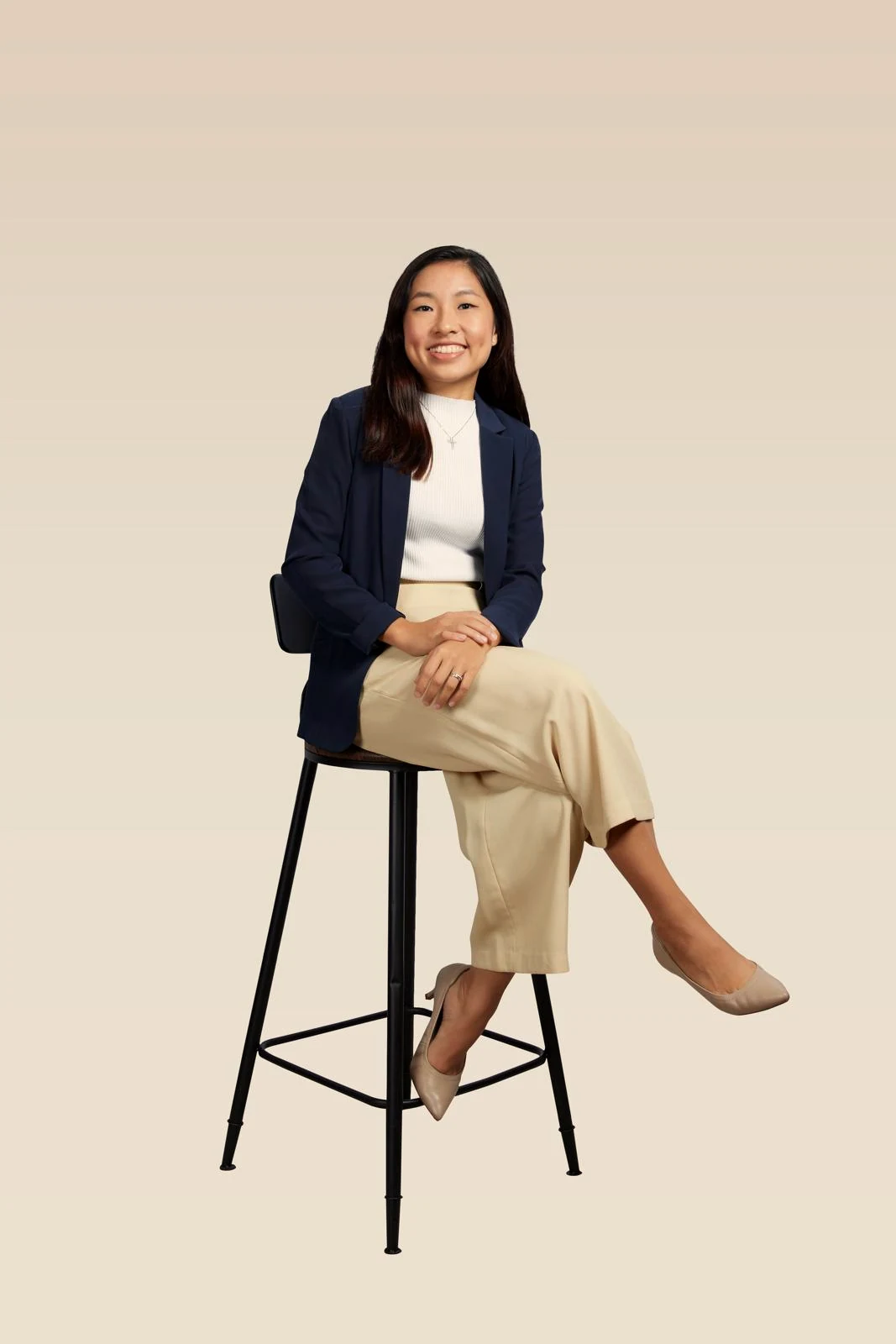 Jessin Chua, seated on a stool in a navy blazer, photographed in the studio.